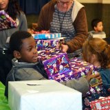 Five-year-old Jaydon Walker enjoying himself with a armful fo presents Friday in the Lemoore Civic Auditorium.